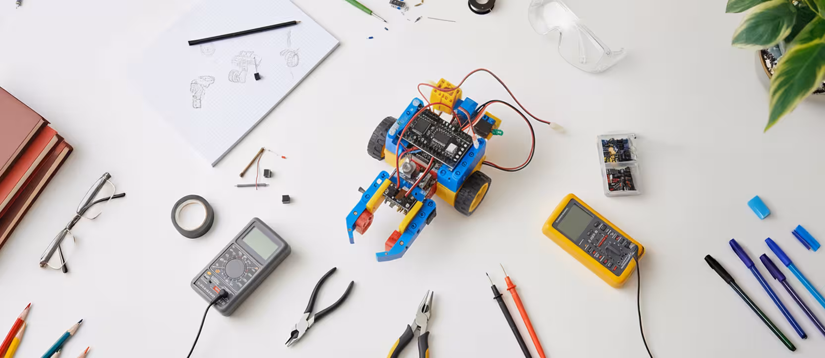 Mesa do Maker Lab com materiais escolares e um robô